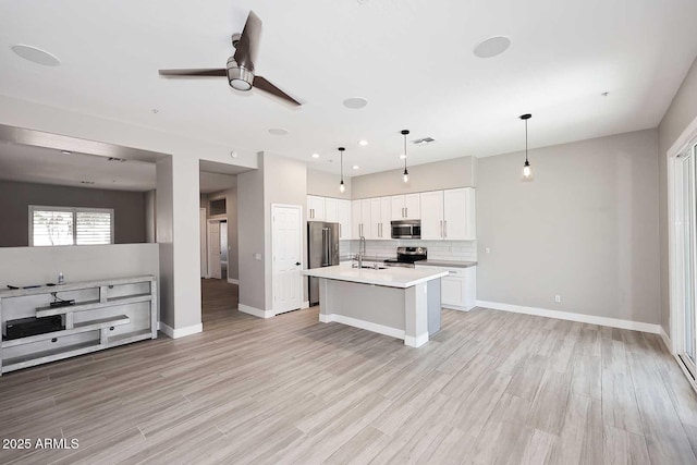 kitchen featuring stainless steel appliances, backsplash, open floor plan, and light countertops