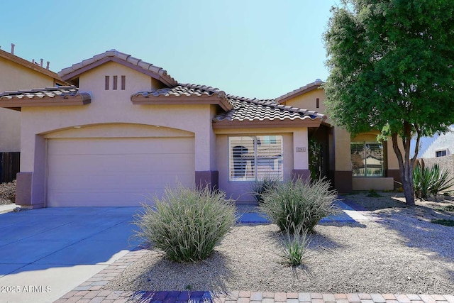 mediterranean / spanish-style house with a tiled roof, stucco siding, an attached garage, and concrete driveway
