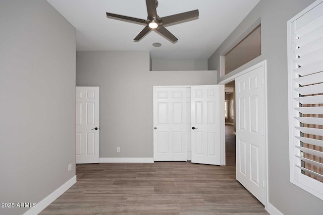unfurnished bedroom with wood finished floors, baseboards, a closet, and ceiling fan