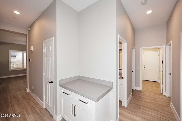 corridor with light wood finished floors, recessed lighting, and baseboards
