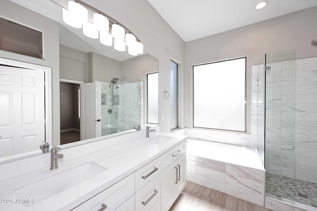 bathroom featuring a bath, a shower stall, double vanity, and a sink