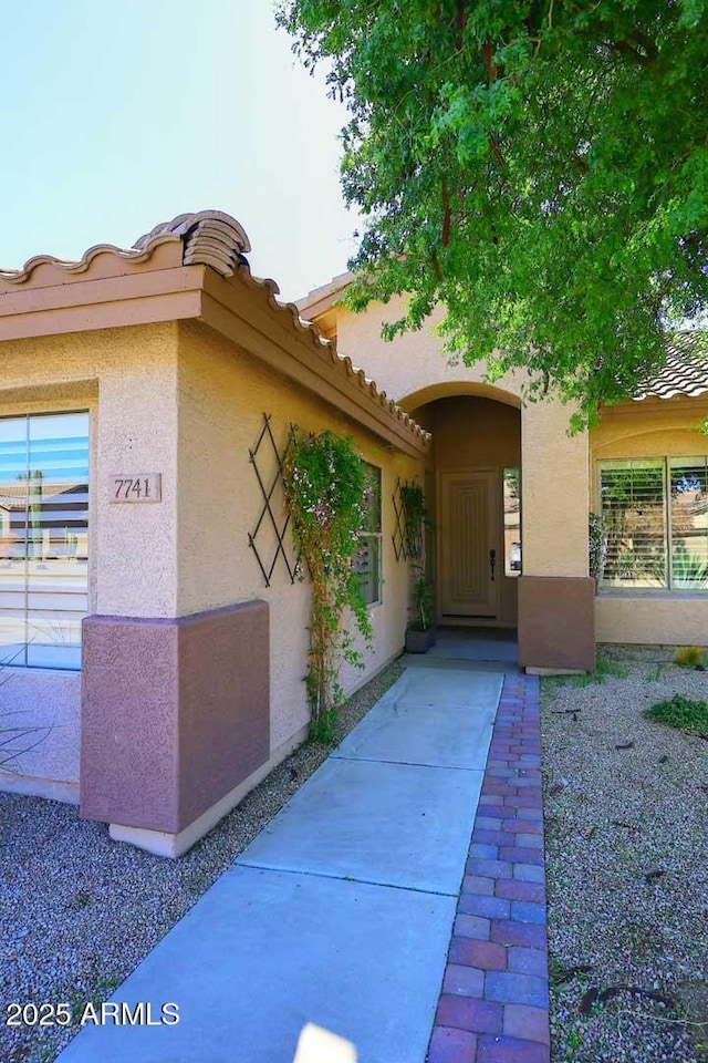 entrance to property featuring stucco siding and a tiled roof