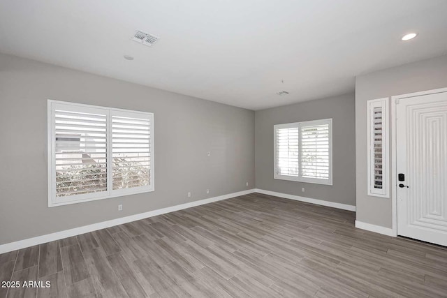 empty room featuring visible vents, recessed lighting, baseboards, and wood finished floors