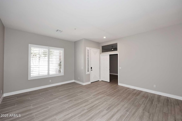 spare room with wood finished floors, baseboards, and visible vents