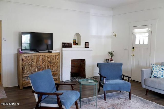 living area with a fireplace with flush hearth and wood finished floors