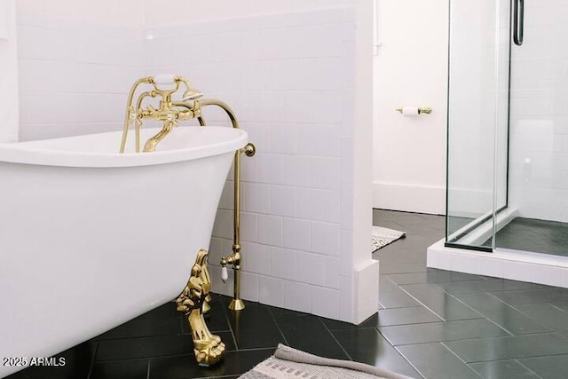 bathroom with tile patterned flooring, a freestanding bath, and a shower stall