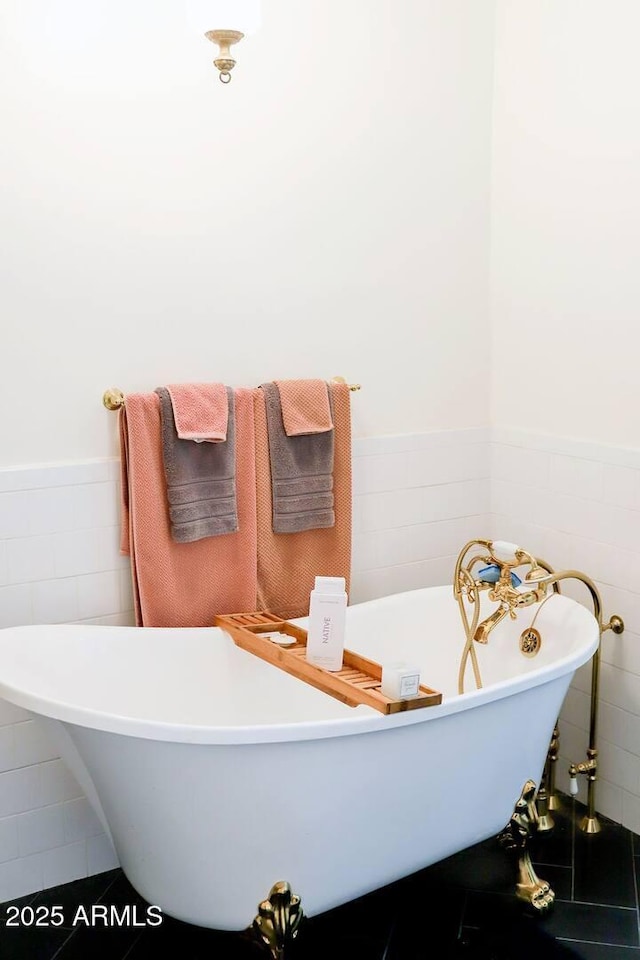 full bathroom with a wainscoted wall, tile walls, and a soaking tub