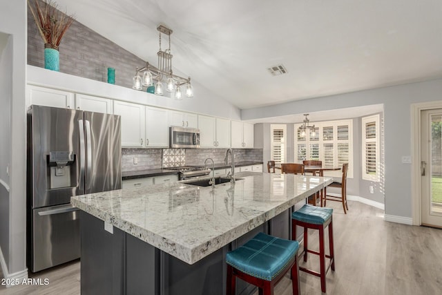 6918 W Villa Hermosa W, Glendale, AZ 85310 - kitchen with stainless steel appliances, a chandelier, decorative backsplash, light wood-style floors, and high vaulted ceiling