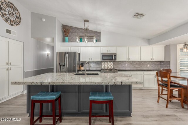 6918 W Villa Hermosa W, Glendale, AZ 85310 - kitchen with stainless steel appliances, lofted ceiling, decorative backsplash, a chandelier, and light wood-style flooring