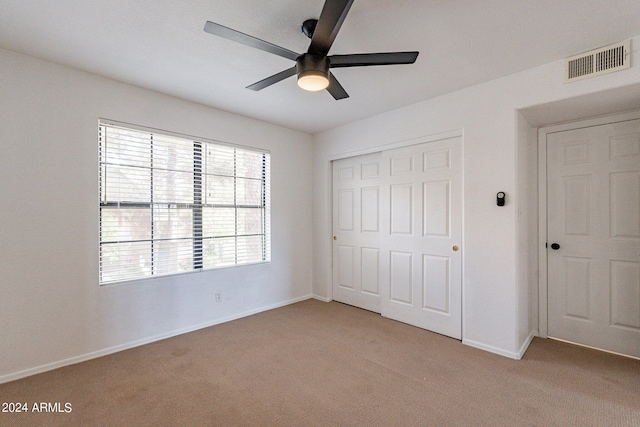 unfurnished bedroom featuring a closet, ceiling fan, and light carpet