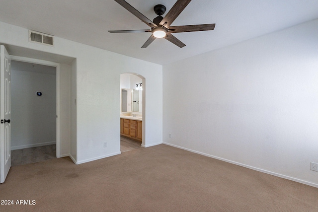 unfurnished bedroom featuring a closet, ceiling fan, light colored carpet, and ensuite bathroom