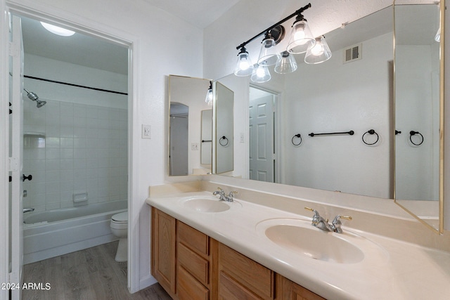 full bathroom featuring toilet, double vanity, tiled shower / bath combo, and hardwood / wood-style flooring