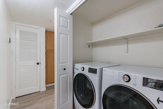 laundry room with washing machine and dryer and light hardwood / wood-style flooring