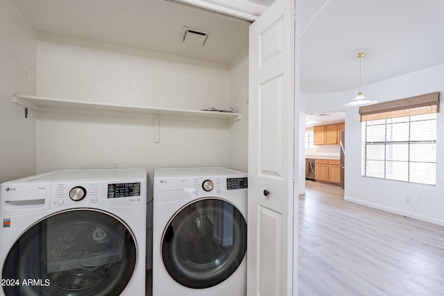 clothes washing area featuring independent washer and dryer and light hardwood / wood-style flooring