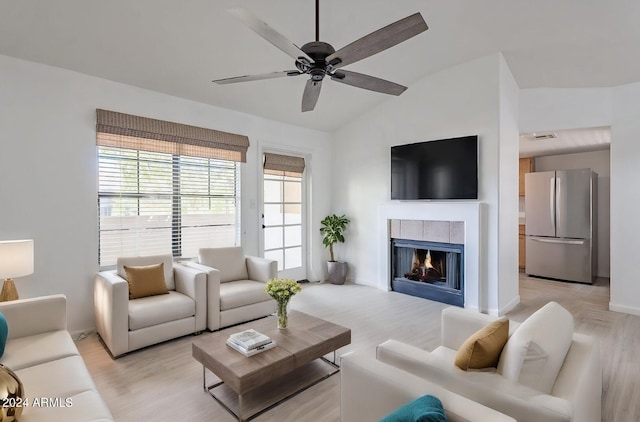 living room with a fireplace, ceiling fan, and vaulted ceiling