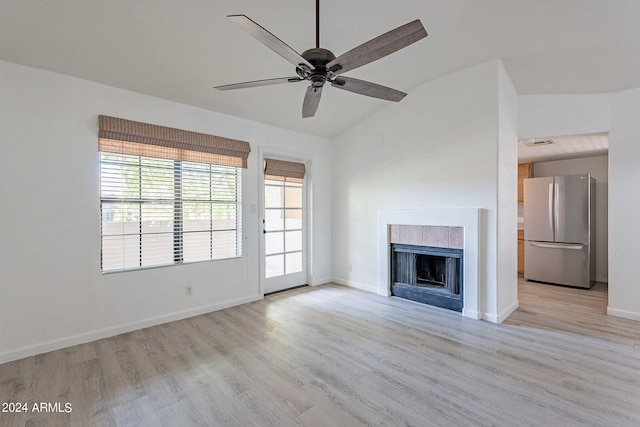 unfurnished living room featuring light hardwood / wood-style floors, a tile fireplace, and ceiling fan