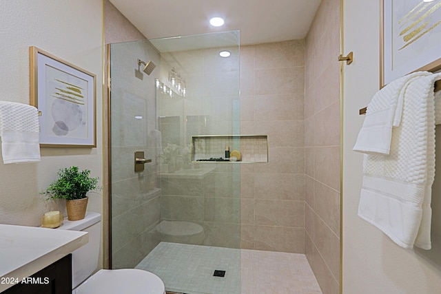 bathroom featuring a tile shower, vanity, and toilet