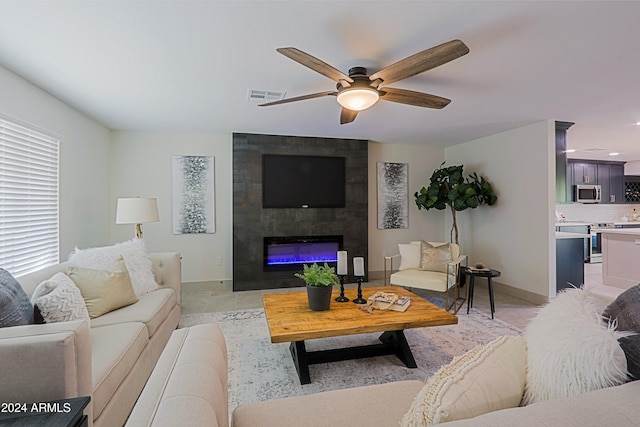 living room with ceiling fan and a tiled fireplace