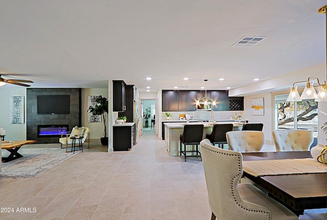 dining space featuring ceiling fan and a tiled fireplace