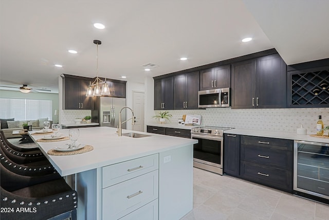 kitchen with stainless steel appliances, sink, decorative light fixtures, a center island with sink, and wine cooler