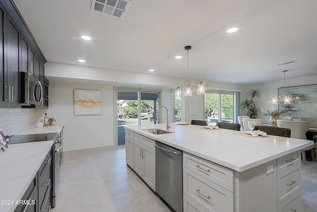 kitchen featuring pendant lighting, backsplash, a center island with sink, sink, and stainless steel appliances