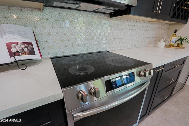 kitchen featuring light stone countertops, light tile patterned floors, backsplash, and high end stainless steel range oven