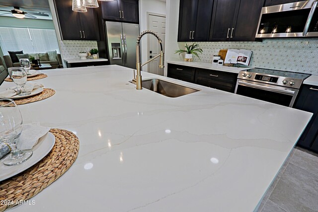 kitchen featuring stainless steel appliances, light stone counters, tasteful backsplash, and sink