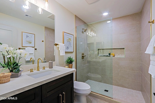 bathroom featuring tile patterned floors, vanity, toilet, and a tile shower