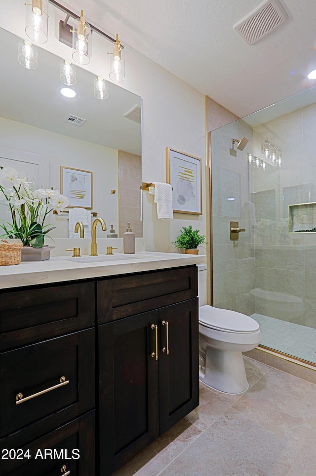 bathroom featuring tile patterned flooring, vanity, toilet, and walk in shower