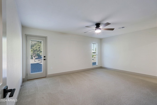 carpeted empty room with a wealth of natural light and ceiling fan