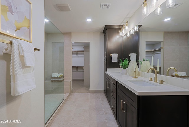 bathroom with tile patterned floors, vanity, and a tile shower