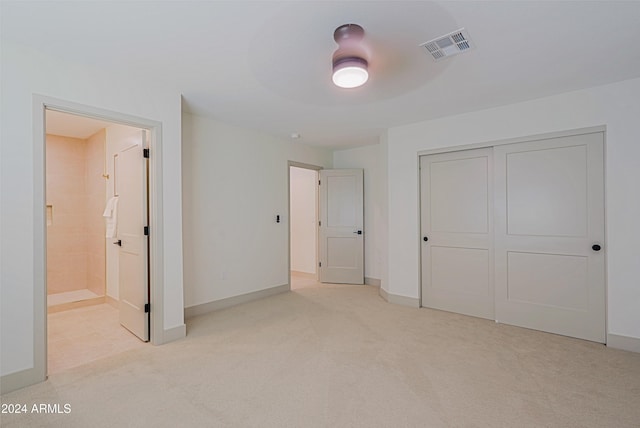 unfurnished bedroom with light carpet, connected bathroom, a closet, and ceiling fan