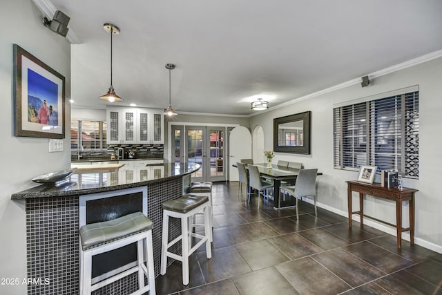 4610 N 14th Ave, Phoenix, AZ 85013 - kitchen with a kitchen bar, decorative backsplash, crown molding, a peninsula, and dark stone countertops