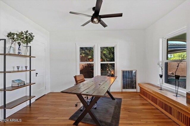 office space with heating unit, a wealth of natural light, hardwood / wood-style floors, and ceiling fan