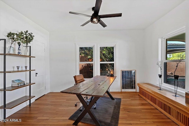 office with heating unit, light wood finished floors, and ceiling fan