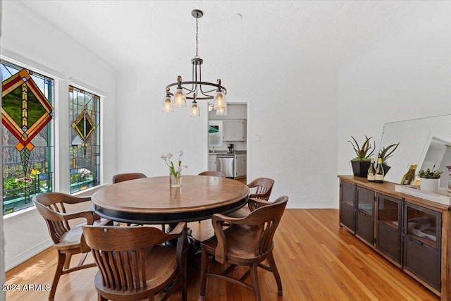 dining area featuring a healthy amount of sunlight, an inviting chandelier, and light hardwood / wood-style flooring