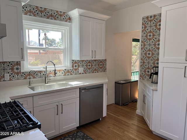 kitchen featuring white cabinetry, a sink, light countertops, dishwasher, and backsplash