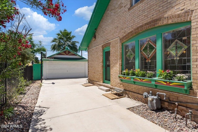 view of home's exterior featuring a detached garage, fence, brick siding, and an outdoor structure