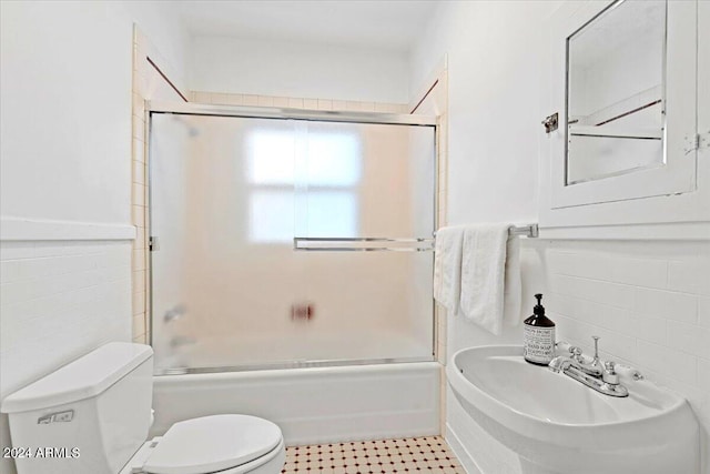 full bathroom featuring tile walls, toilet, sink, and enclosed tub / shower combo