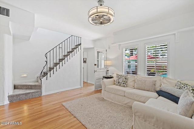 living room featuring visible vents, stairs, baseboards, and wood finished floors