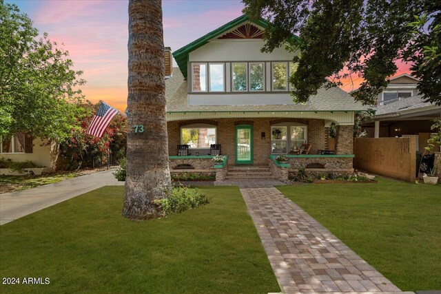 tudor-style house featuring a lawn and covered porch