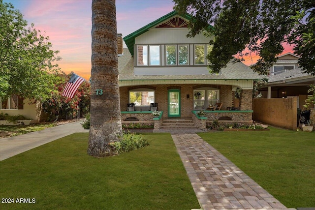 english style home with a porch, brick siding, and a front yard