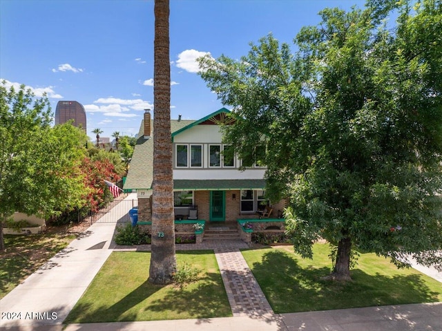 view of front of property featuring a front lawn, a porch, brick siding, and a chimney