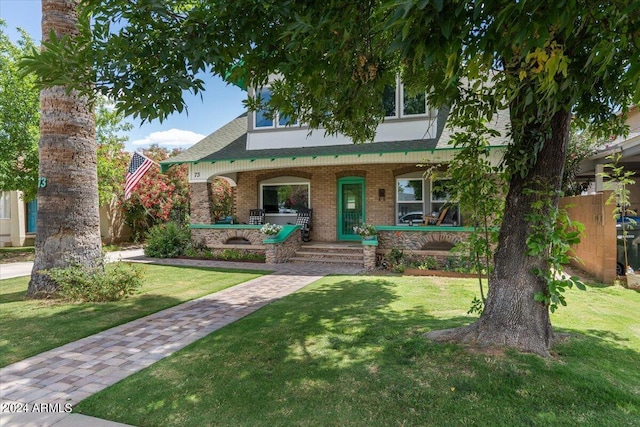 view of front of house with a front lawn, brick siding, and covered porch