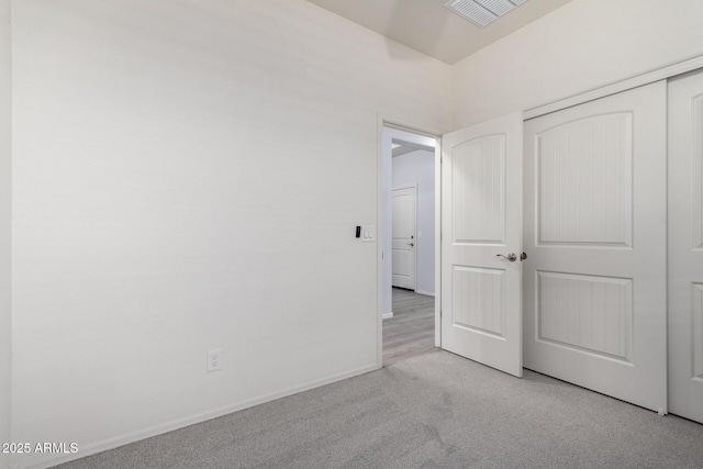 unfurnished bedroom featuring light carpet and a closet