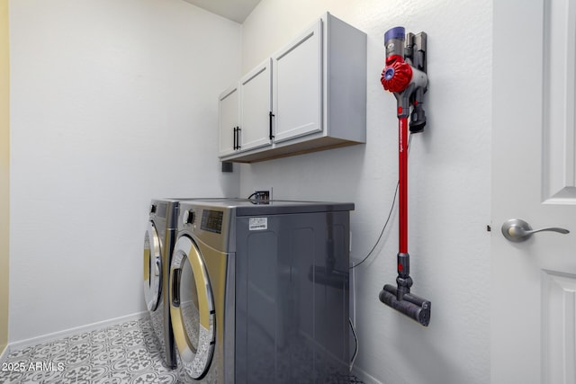 clothes washing area featuring cabinets, washing machine and dryer, and light tile patterned floors