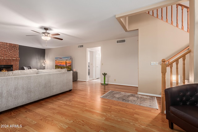 living room featuring ceiling fan, light hardwood / wood-style floors, and a fireplace