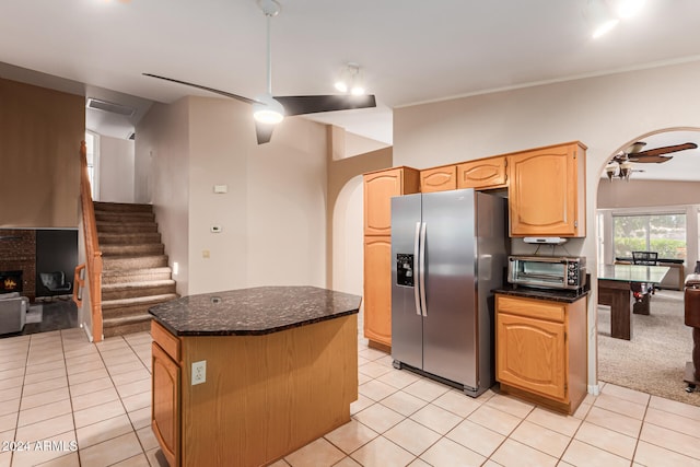 kitchen featuring stainless steel fridge with ice dispenser, light brown cabinets, light colored carpet, ceiling fan, and a center island