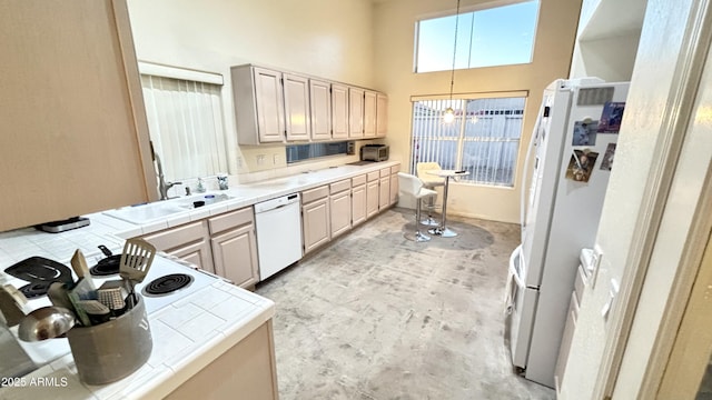 11854 E Carol Ave, Scottsdale, AZ 85259 - kitchen with white appliances, tile counters, a towering ceiling, a chandelier, and decorative light fixtures