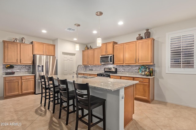 kitchen with a kitchen bar, sink, hanging light fixtures, a center island with sink, and appliances with stainless steel finishes